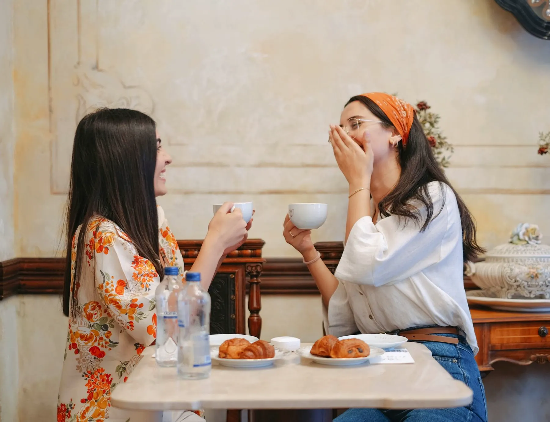 Twee vrouwen lachen samen bij de koffie, zonder script