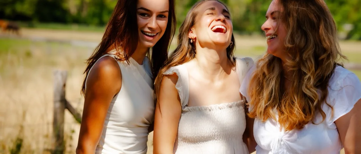 Drie vrouwen van de community lachen samen buiten in het groen